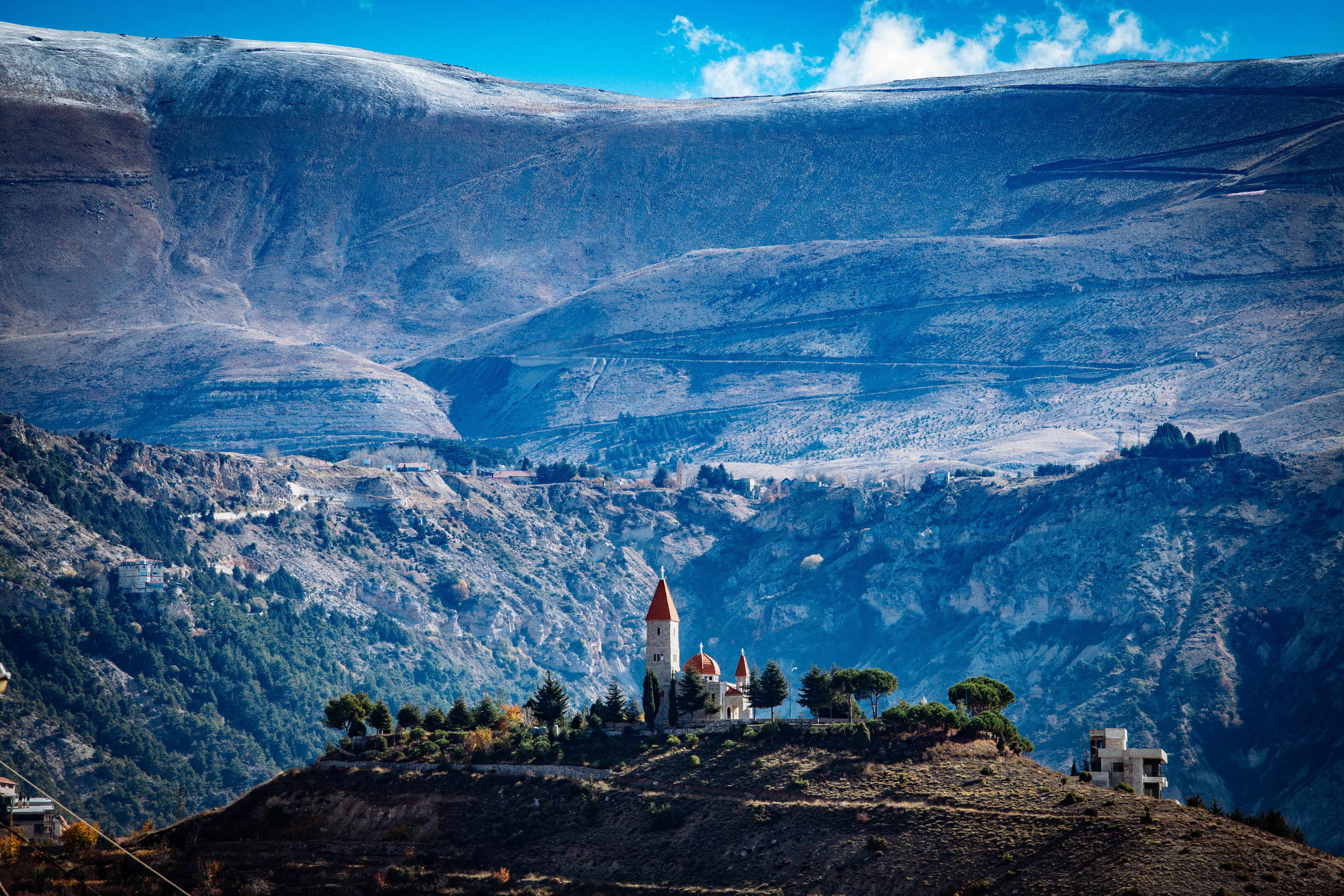 Die Herz-Jesu-Kirche mit dem Libanongebirge im Hintergrund auf einem Hügel ragt über dem Wadi Qadischa, dem „Heiligen Tal“. Jahrhunderte lang diente die tiefe Schlucht mit ihren steilen Felswänden verfolgten Christen als Zufluchtsort. Foto: © Hartmut Schwarzbach / missio